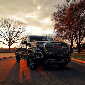 Black truck parked at sunset in a city park.