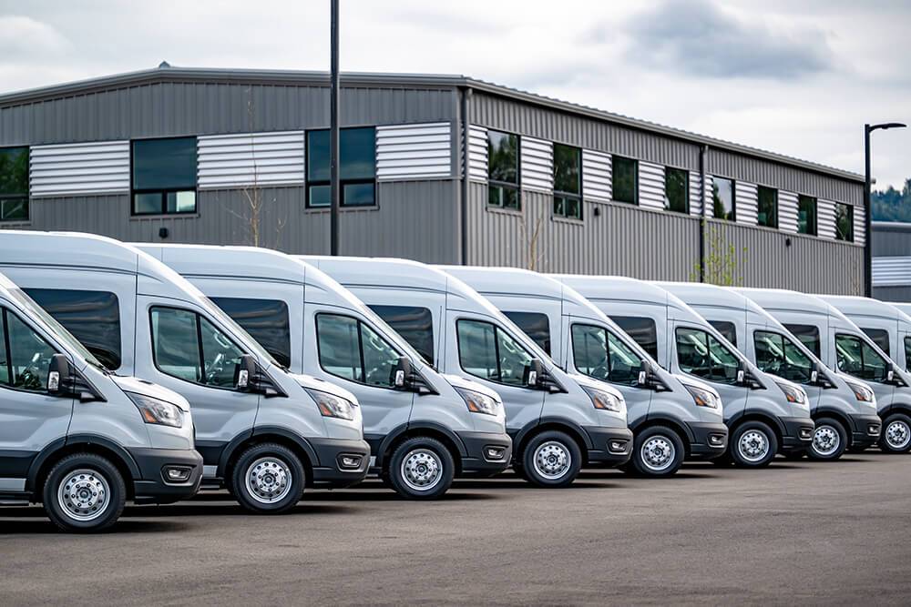 Row of gray delivery vans outside warehouse