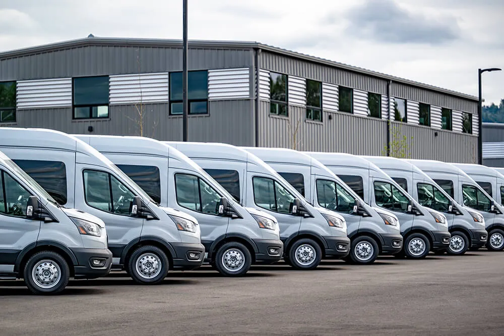Row of gray delivery vans outside warehouse