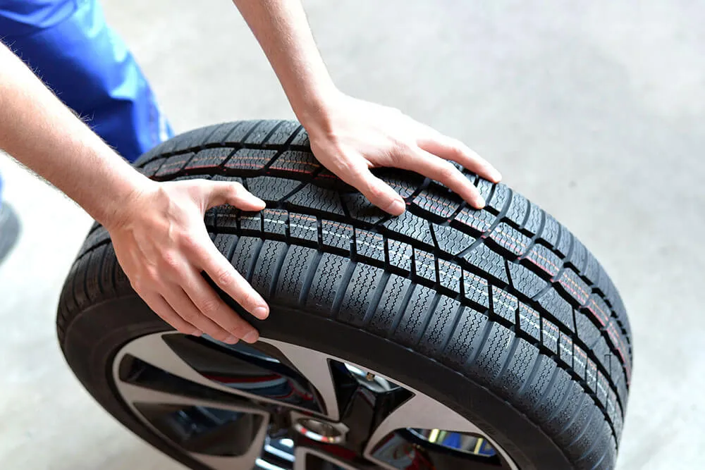 Mechanic inspecting car tire tread for safety.